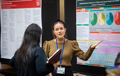 AUCD Emerging Leader gesturing towards poster.